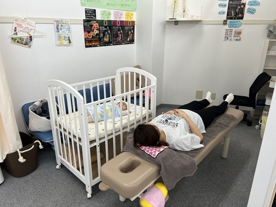 子供の隣で骨盤矯正の施術を受けている様子